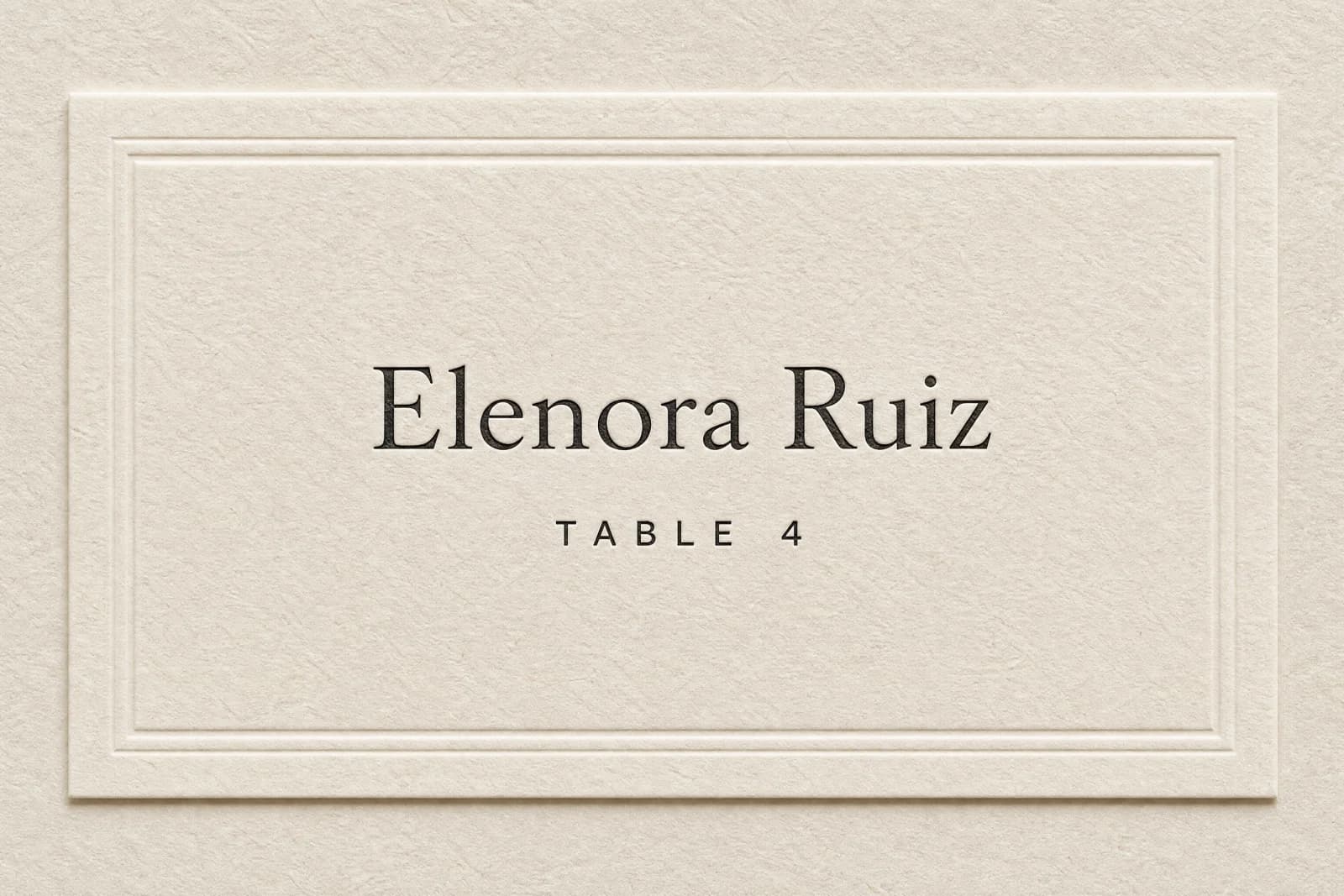A finished wedding place card lying on embossed cream paper